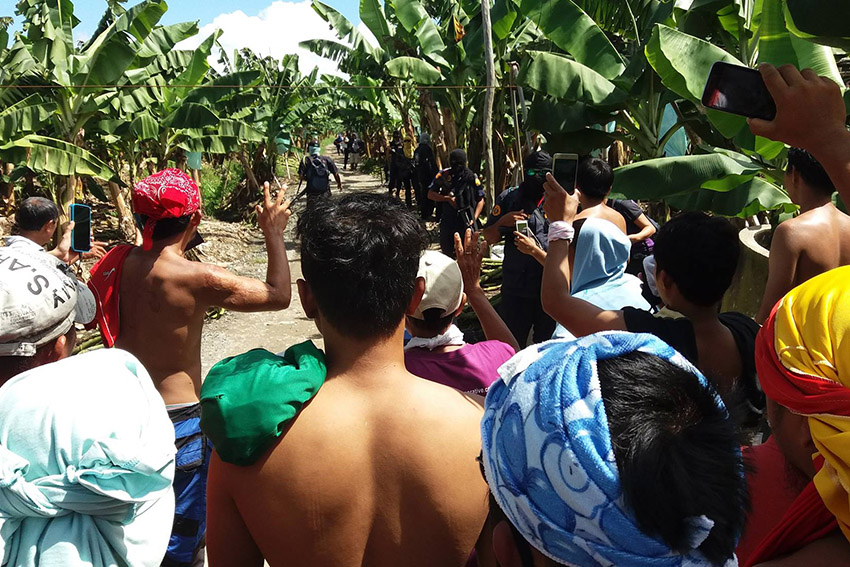 As security guards of Lapanday Food Corporation fired warning shots against protesting farmers in Tagum City on Friday, Dec. 9, the farmers took off their shirts to show that they are unarmed and should not be accused of bringing guns in the protest site. The farmers are claiming a portion of the land from the banana company.  (Photo from Kilab Multimedia) 