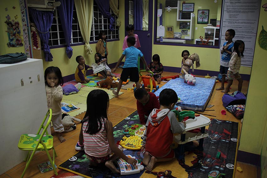 PLAY TIME. Children spend their time playing inside the Barangay Matina's child minding center unmindful of the intermittent rain that caused the swelling of the Matina Pangi river to alarming levels on Monday evening, January 2. (Paulo C. Rizal/davaotoday.com) 