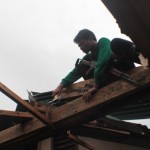 FIXING. A communist guerilla helps repair the roof of one of the families affected by typhoon Pablo in Compostela Valley province. (davaotoday.com photo by Ace R. Morandante)