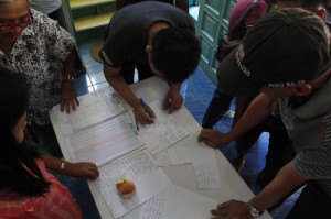 LISTING. Voters in Buhangin Elementary School search for their names in the voters' list with the help of teachers acting as election tellers, but some end up frustrated not finding their names. (davaotoday.com photo by Ace R. Morandante)