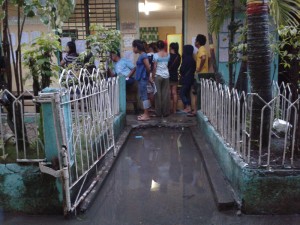 FLOOD. Flood from the afternoon rain did not stop these people from watching the counting of votes in SIR Elementary School. (davaotoday.com photo by Tyrone A. Velez)