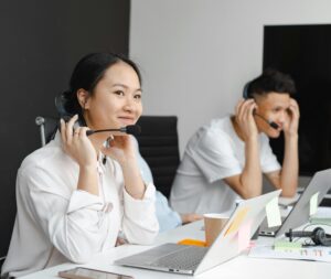 A diverse group of call center agents working with laptops and headsets in a modern office.